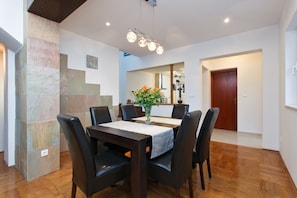 A dining area with a wooden table, black chairs, and a vase of flowers. There is a staircase on the left and a door on the right. - Beach house, 4 people, private pool, garden, terrace, family & kids (Sutomišcica)