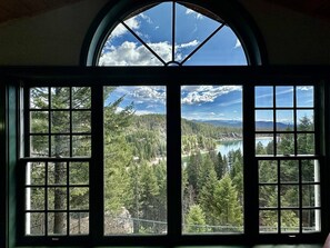 Ein großes, rundes Fenster mit Blick auf eine bewaldete Landschaft und einen See.