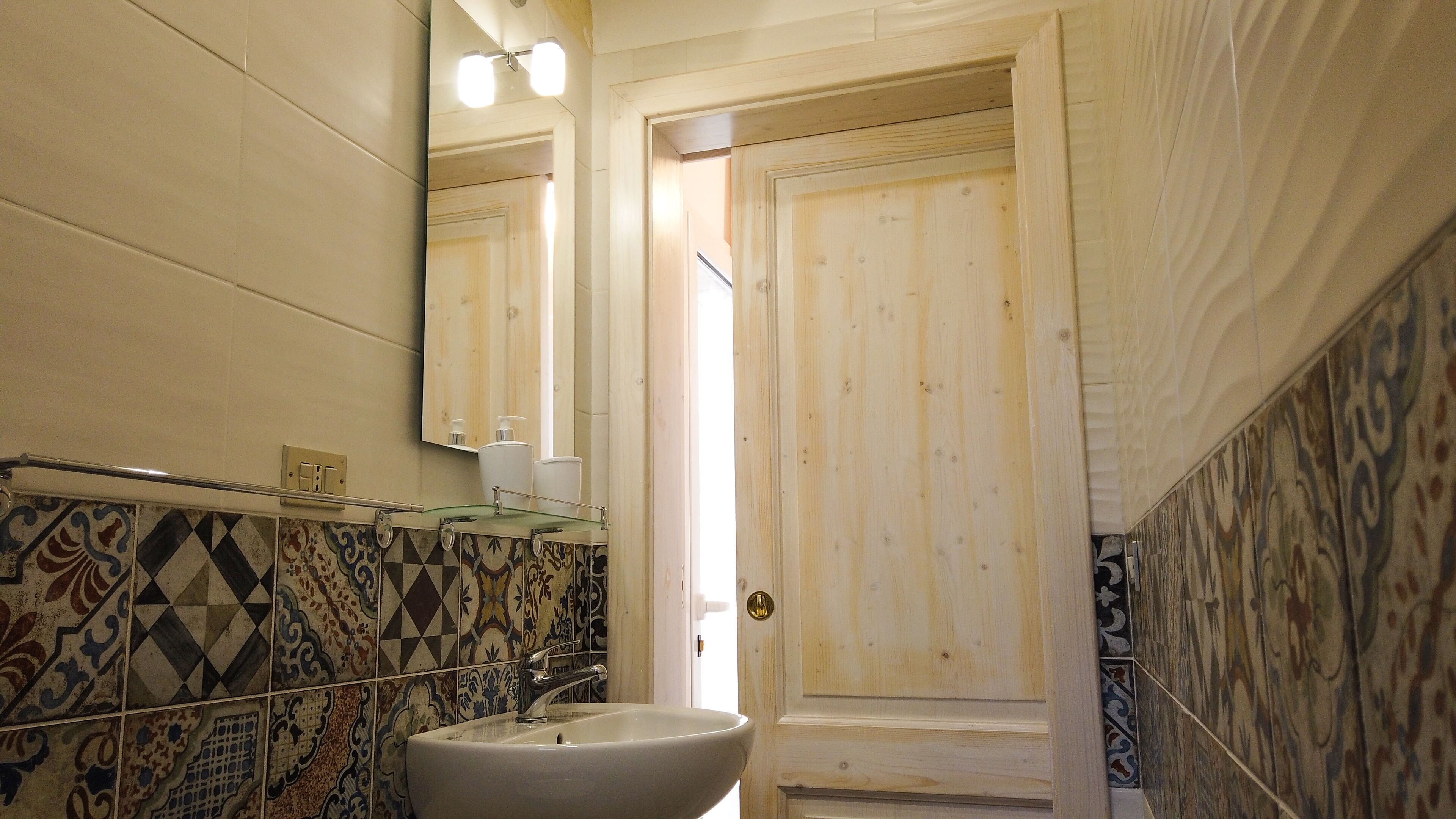 A bathroom with a sink, mirror, and patterned tiles.