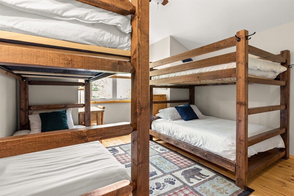 A bunk bed room with wooden frames and white bedding.