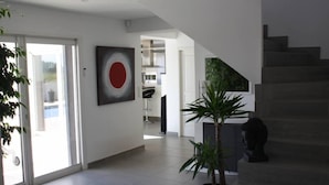 Un vaste espace de vie agrémenté d’un escalier, d’une plante en pot et d’une œuvre d’art moderne accrochée au mur.