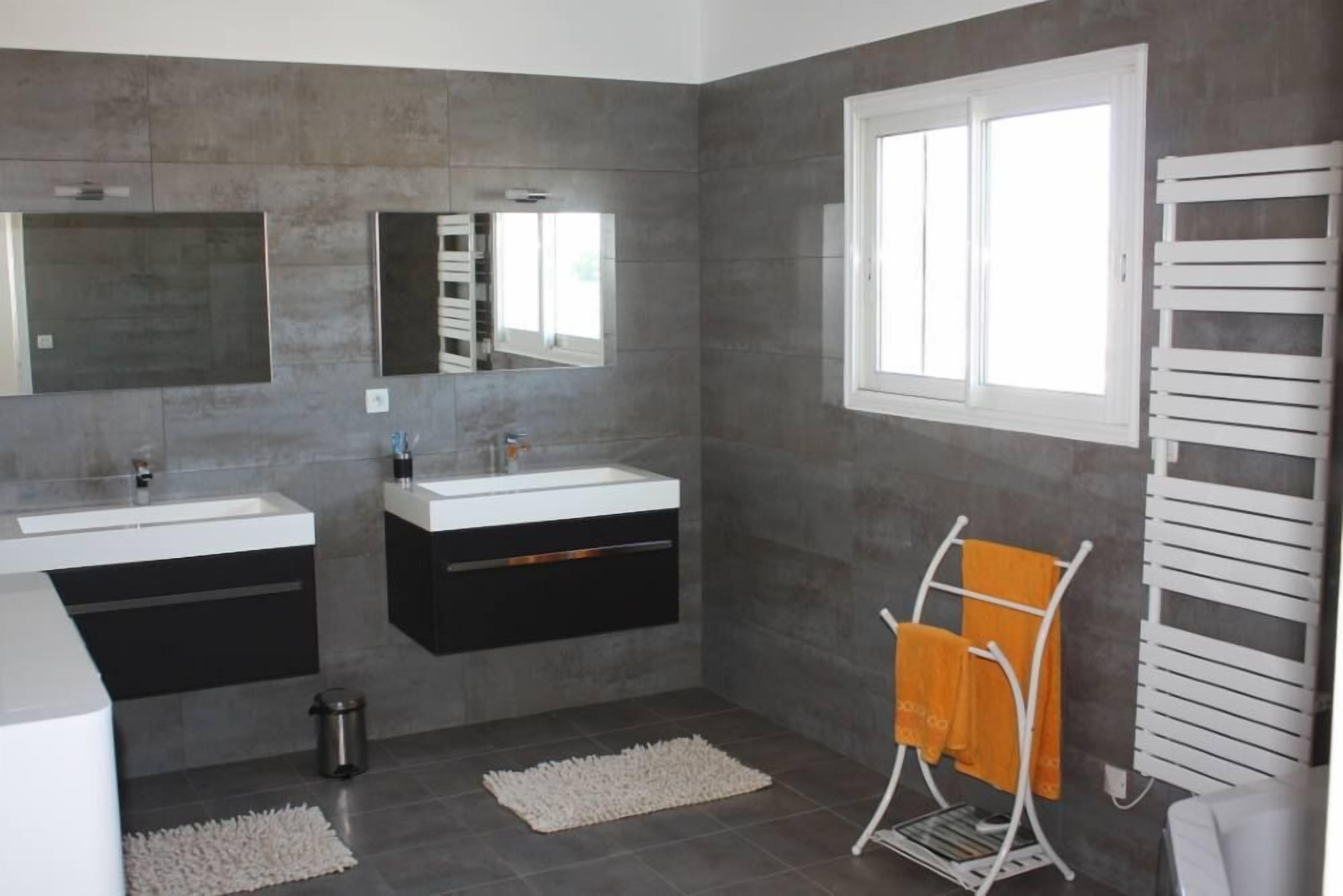 A modern bathroom with two sinks, a large mirror, and a towel rack.