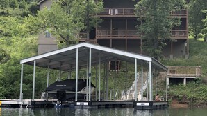 A covered dock with a boat, a swimming pool, and a building with multiple balconies in the background. - CONVENIENCE! Steps away to a private dock & 5 miles to a marina/grocery/hwy!    (Caryville)