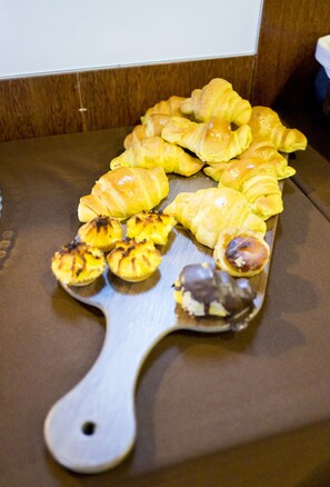 Une planche en bois servant de présentoir, avec des croissants et de petites pâtisseries disposés sur une table.