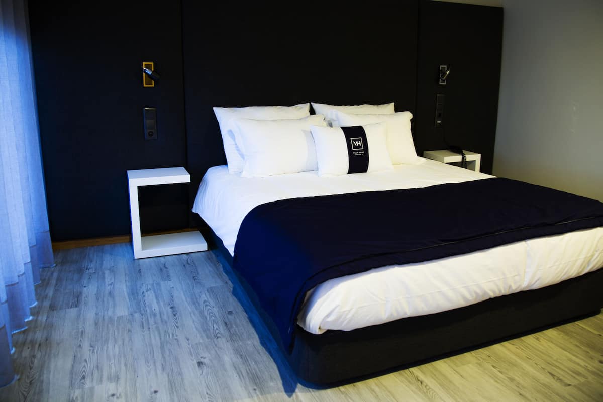 Une chambre d’hôtel moderne avec un grand lit, une table de chevet et une petite table d’appoint.