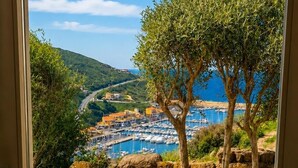 A view through a door of a coastal area with a marina, olive trees, and a paved patio. - Luxury apartment with stunning sea views and close to sea and shops, WI-FI,clima (Castelsardo)