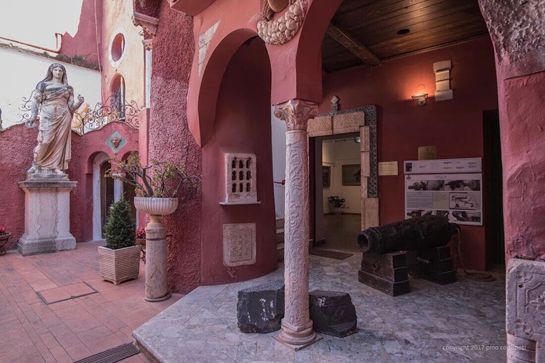 Ein Innenhof mit einer Statue, Säulen und einer Kanone.