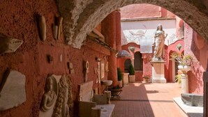 An interior courtyard with a central statue, stone carvings on the walls, and potted plants. - La Ninfa Di Capri (Anacapri)