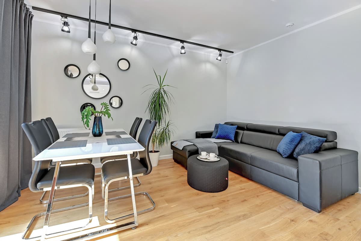A modern living room with a grey sofa, a dining table with chairs, and a coffee table.