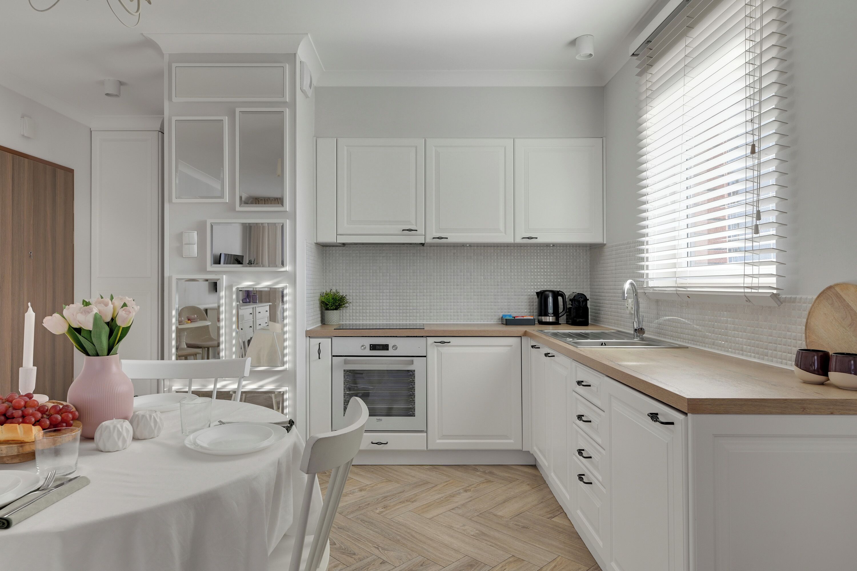 Una cocina moderna con armarios blancos, encimera de madera y horno integrado.