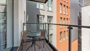 En balkon med et bord og stole, med udsigt over en bygning i en blanding af mursten og moderne stil.