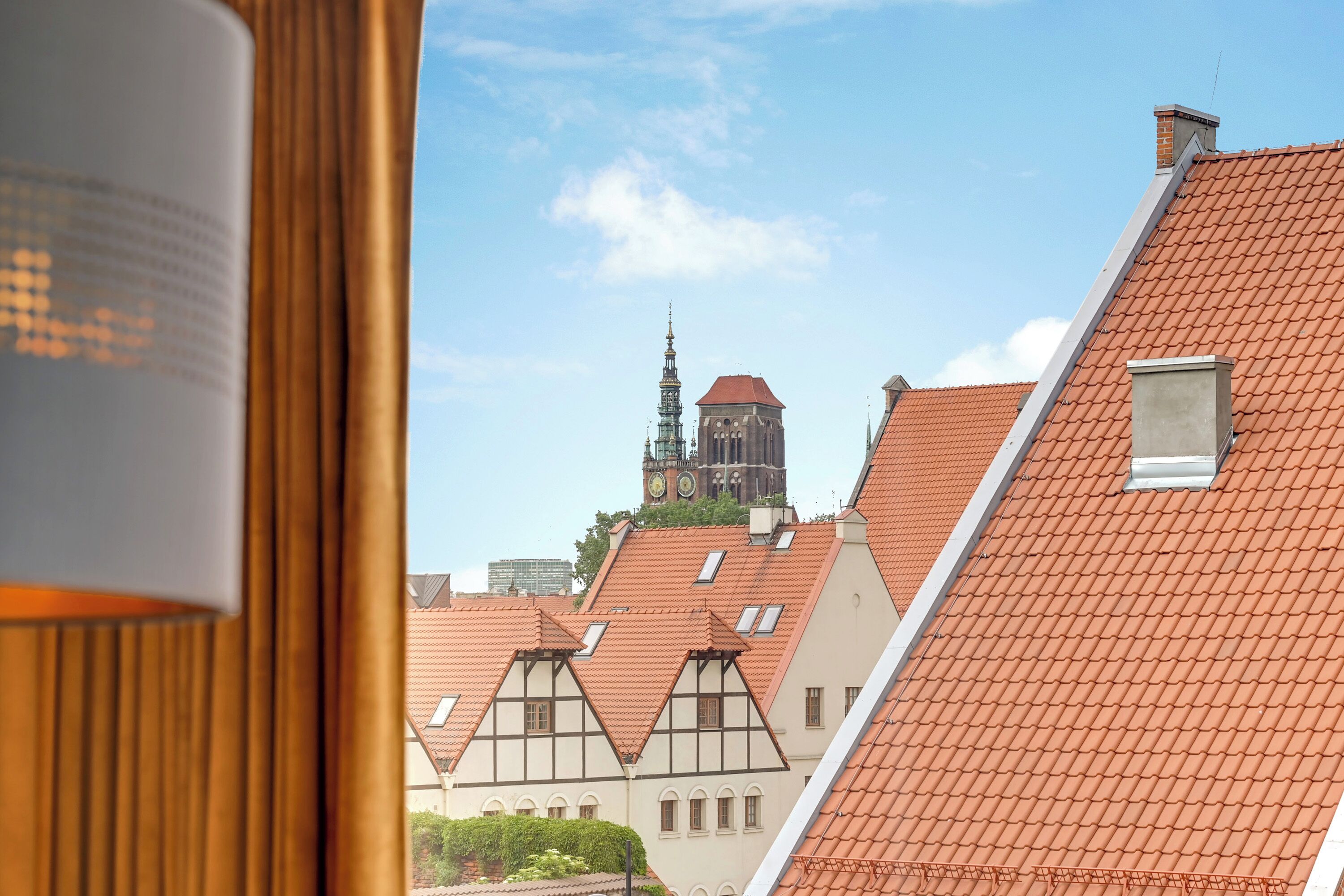 Vista de arquitectura europea tradicional, con tejados rojos y una imponente torre del reloj al fondo.