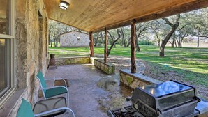 Un patio coperto con pareti in pietra, un barbecue e posti a sedere all'aperto.