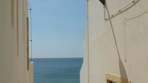 Eine enge Treppe führt zu einem Balkon mit Blick auf einen Strand.
