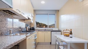 Een moderne keuken met granieten aanrecht, een vaatwasser, een raam met uitzicht op de heuvels en een eethoek met een witte tafel en stoelen.