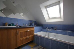 A modern bathroom with a skylight, a bathtub, and a wooden vanity. - House / Villa - Baden (Baden)