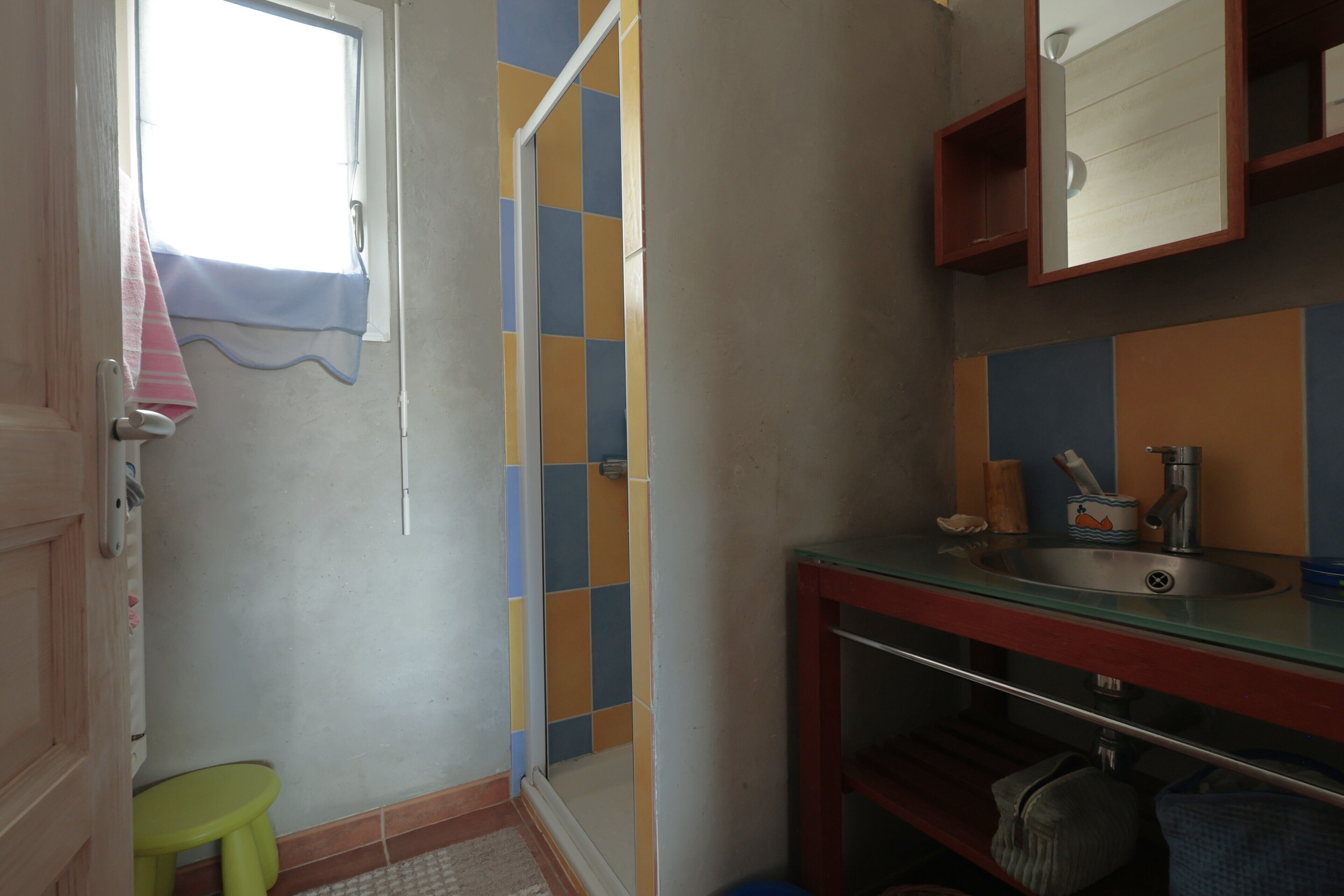 Ein kleines Badezimmer mit Dusche, Waschbecken und Spiegel.