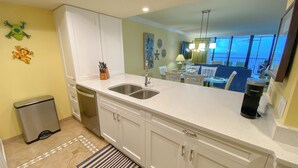 A modern kitchen with white cabinets, a double sink, and a stainless steel refrigerator. - Sanibel Harbour Resort Harbour Tower 713:   Relaxing in the tropics in this beach themed condo (Fort Myers)