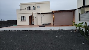 Ett modernt hus med ett platt tak, en balkong och en carport.