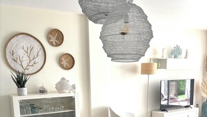 Un espace repas moderne avec une table en verre, des chaises en osier et un centre de table en forme de saladier en bois.