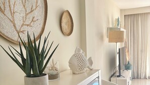 Un salon moderne avec une console blanche, une vitrine en verre, un fauteuil blanc et une grande œuvre d’art murale.