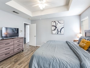 A bedroom with a bed, a TV on a dresser, a ceiling fan, and a painting on the wall. - Cozy Executive Home in Central Frisco (Frisco)