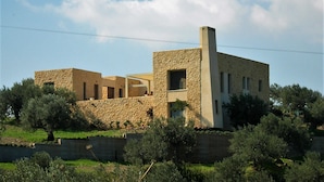 Un edificio de piedra con chimenea, rodeado de follaje y árboles.