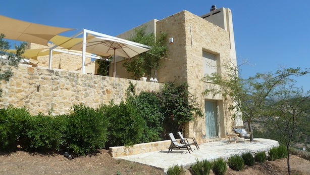 Un edificio de piedra con patio, mobiliario exterior y un espacio cubierto con sombrillas.