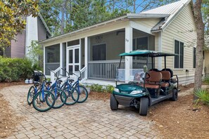 A covered porch with a golf cart and bicycles parked outside.