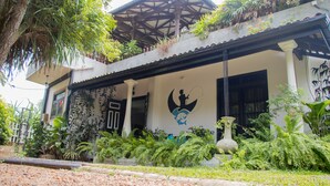 A two-story building with a covered porch, a mural, and lush greenery. - Whispering Ocean (Panadura)