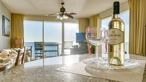 Et spisebord med en flaske Clos du Bois Pinot Grigio vin, to glas og en dekorativ pebermynte-slikkepind. Værelset har havudsigt gennem store vinduer.