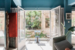 A room with a large glass door leading to an outdoor area, a red textured wall, and a modern chair. - Central Comfy Apt with Private Balcony & Rooftop Access. CT3 (Athens)