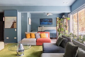 A modern bedroom with a bed, a sofa, a glass coffee table, and a ceiling fan. - Central Comfy Apt with Private Balcony & Rooftop Access. CT3 (Athens)