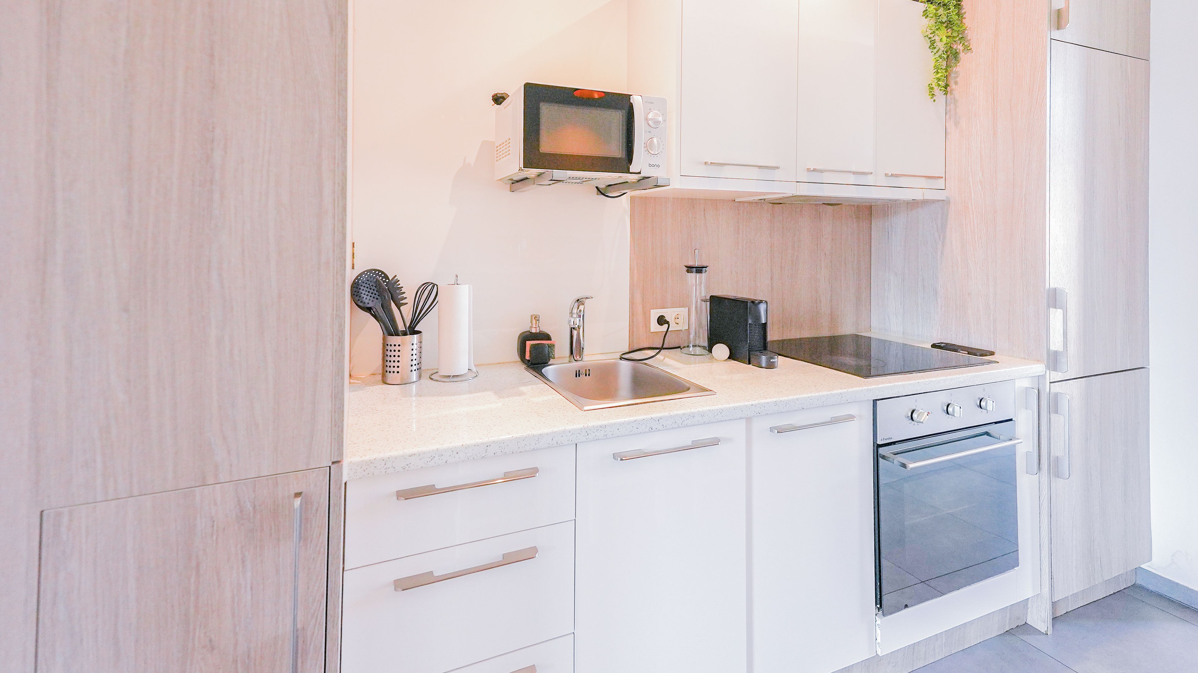 A modern kitchen with white cabinetry, a built-in microwave, a sink, a stove, and an oven.