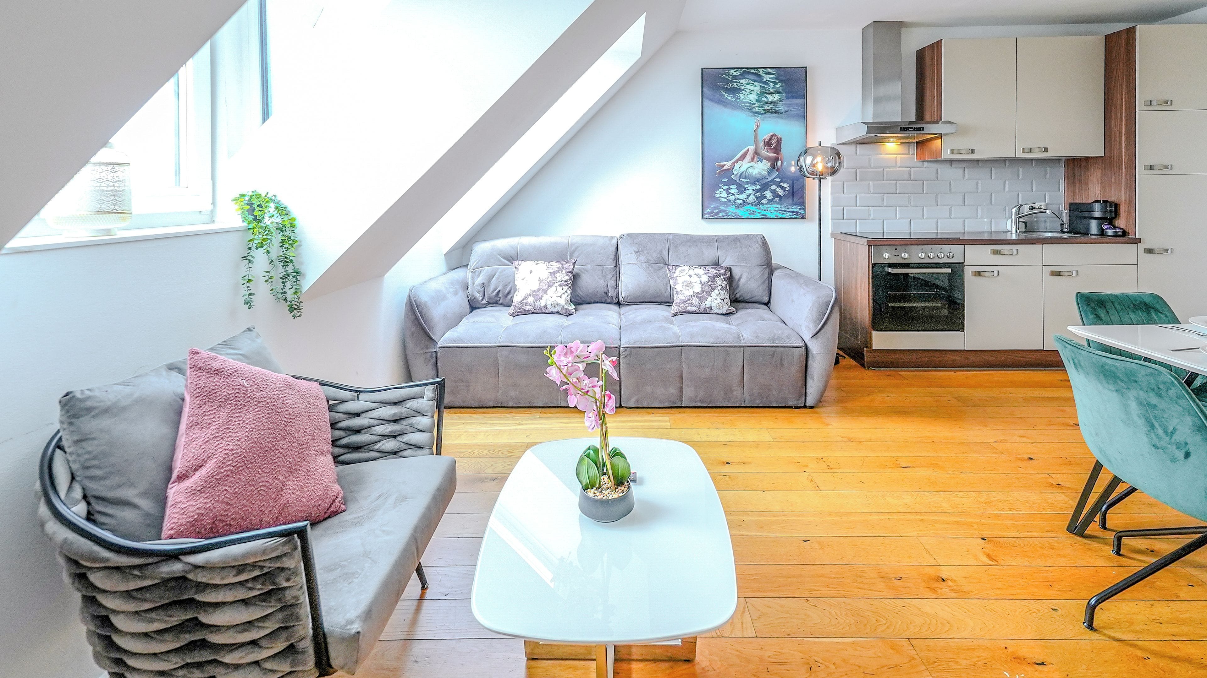 Eine moderne Loft-Wohnung mit Essbereich, einer Couch, einem kleinen Tisch und einer Küche mit Herd und Schränken.
