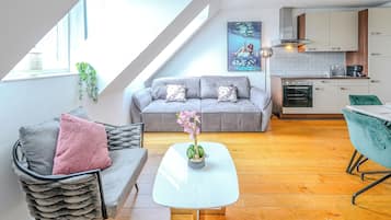Eine moderne Loft-Wohnung mit Essbereich, einer Couch, einem kleinen Tisch und einer Küche mit Herd und Schränken.