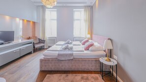 A modern hotel room with a bed, bedside table, lamp, and a desk with a television. - Christiano Apartments (Vienna)