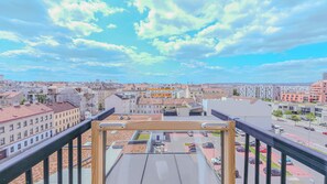 A cityscape viewed from a high vantage point, featuring a variety of buildings, a clear sky, and a parking area below. - Christiano Apartments (Vienna)