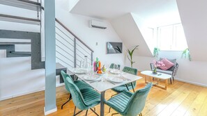 A modern dining area with a high ceiling, a staircase, and a dining table set for four. - Christiano Apartments (Vienna)