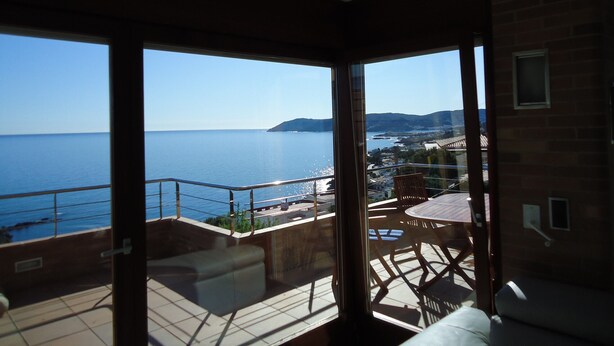 A balcony with a view of the sea and distant hills.