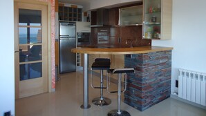 A modern kitchen with a central island, stainless steel appliances, and a stone accent wall.