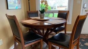 Un coin repas avec une table ronde en bois, quatre chaises et une plante en pot.