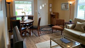 Un salon comprenant un canapé, une table basse, une table à manger avec des chaises, un téléviseur et une porte ornée de panneaux de verre décoratifs.