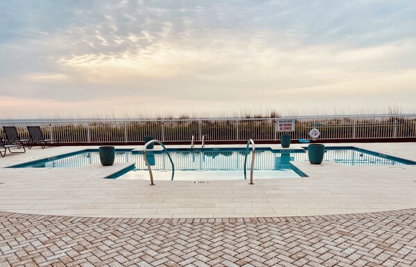 A swimming pool with a view of the beach and a sign indicating no diving allowed.
