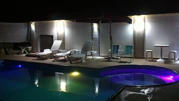 Una piscina al aire libre, sillones reclinables de piscina