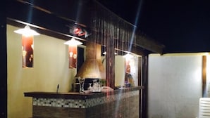 A bar area with a tiled counter, hanging lights, and a large copper pot. - Pousada Requinte da Mantiqueira (Piracaia)