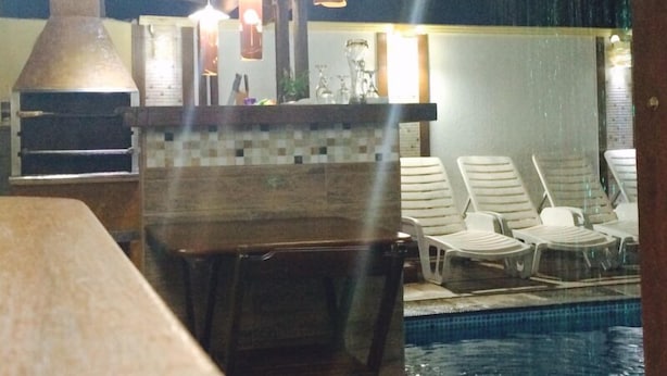 A poolside area with lounge chairs, a pool, and a brick oven. - Pousada Requinte da Mantiqueira (Piracaia)
