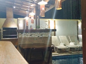 A poolside area with lounge chairs, a pool, and a brick oven. - Pousada Requinte da Mantiqueira (Piracaia)
