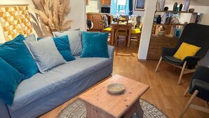 Ein Wohnzimmer mit einem grauen Sofa, einem Holztisch und einem gemusterten Teppich.