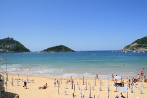 Una playa con sombrillas, gente y cielo despejado.